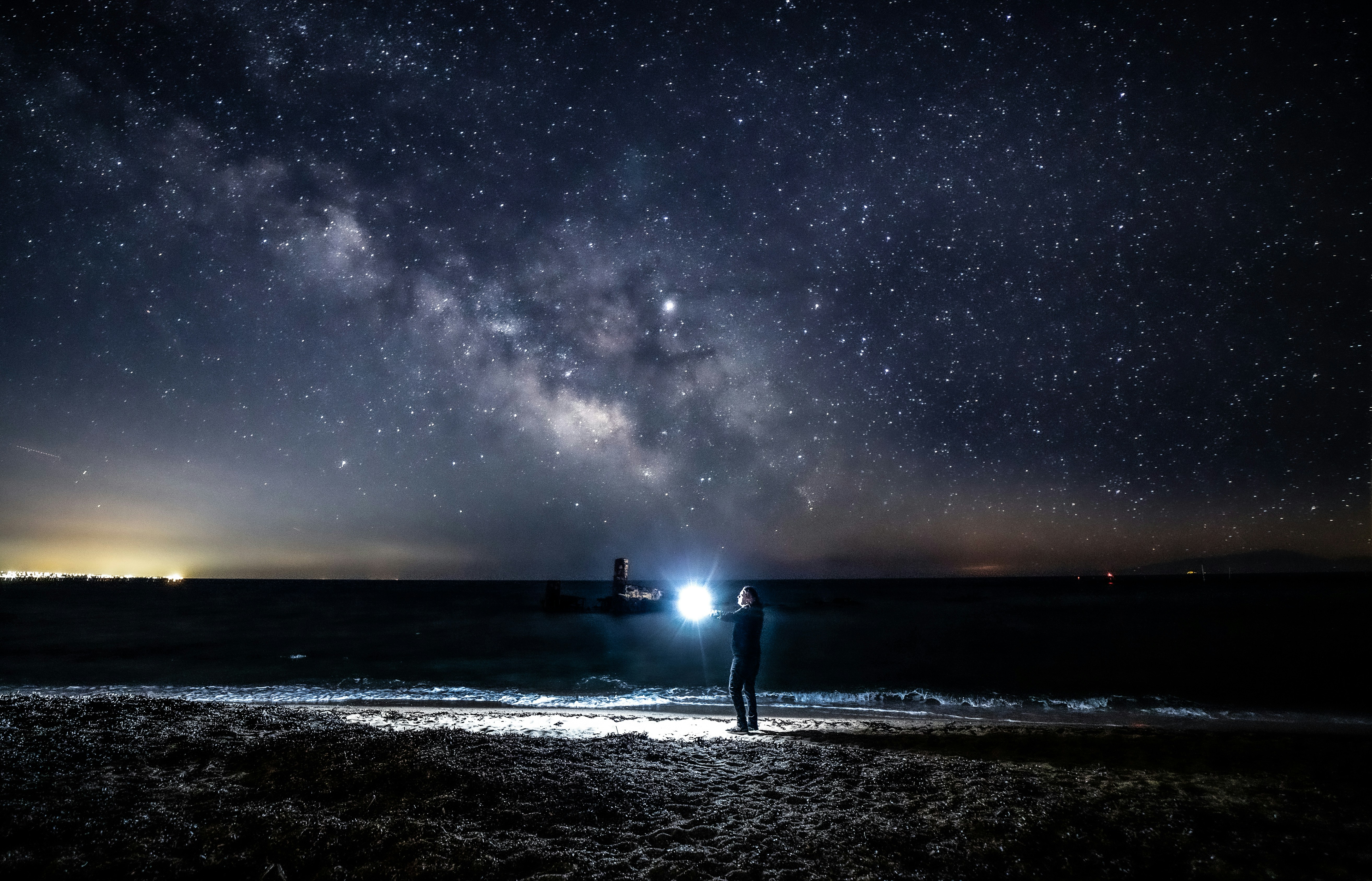 man standing beside sea under milky way