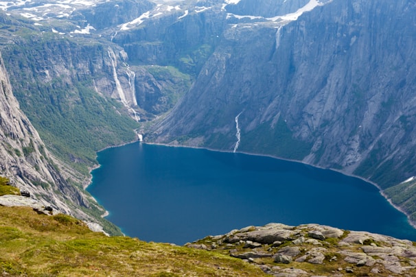 A pristine waterfall cascading into a crystal-clear fjord, surrounded by lush greenery.