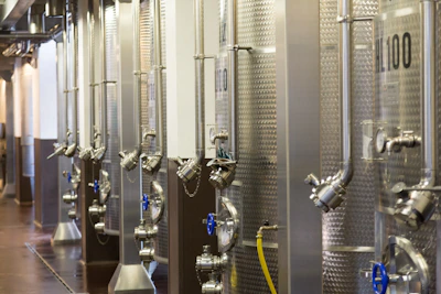 Rows of large stainless steel tanks used for extracting carrier oils in a clean factory setting.