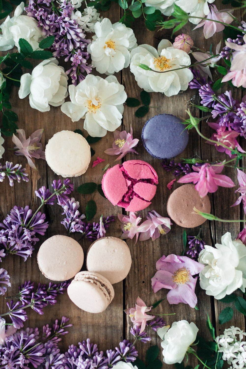 Flatlay-Foto von französischen Macarons, umgeben von Blumen