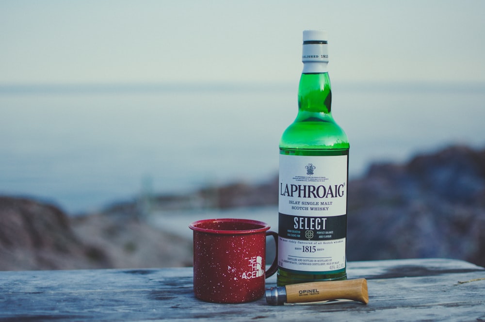 red mug beside wine bottle