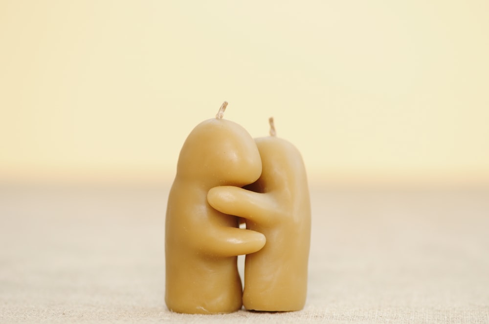 two beige hugging candles on white surface