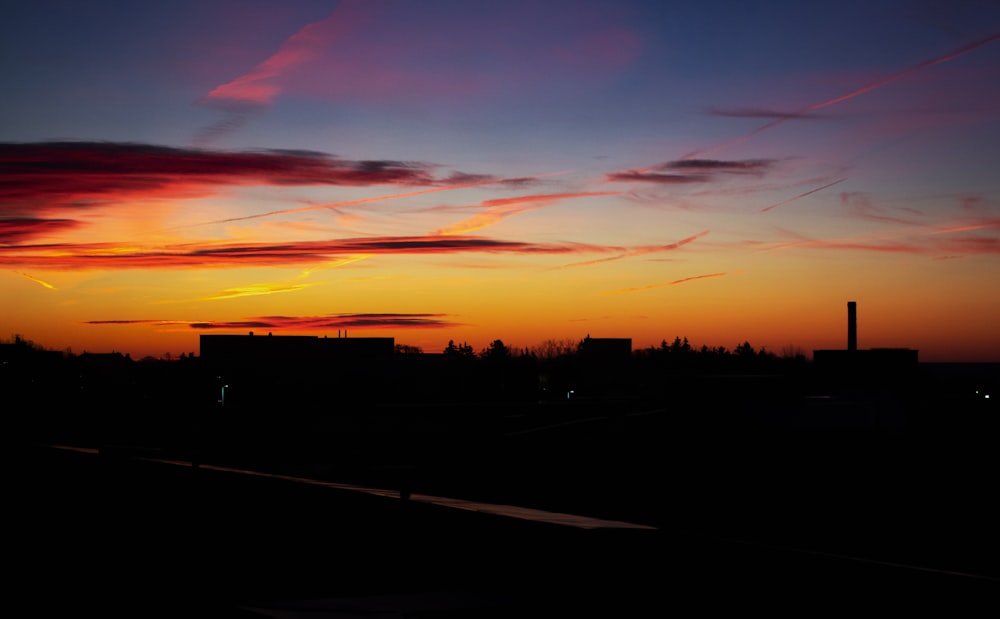 silhouette of building and trees under orange skies