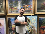 A smiling artist standing proudly beside a vibrant, abstract painting.