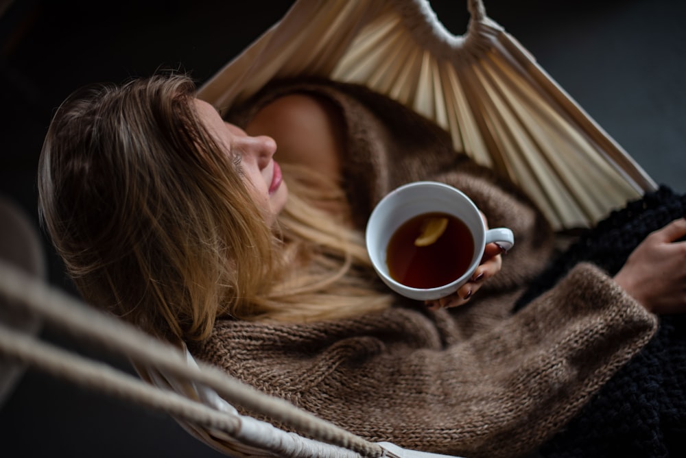 woman on hammock holding cup of coffee