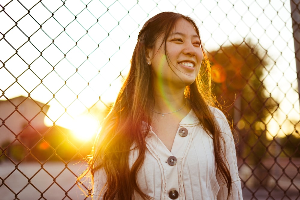 Mujer sonriendo frente a la cerca de alambre durante la hora dorada