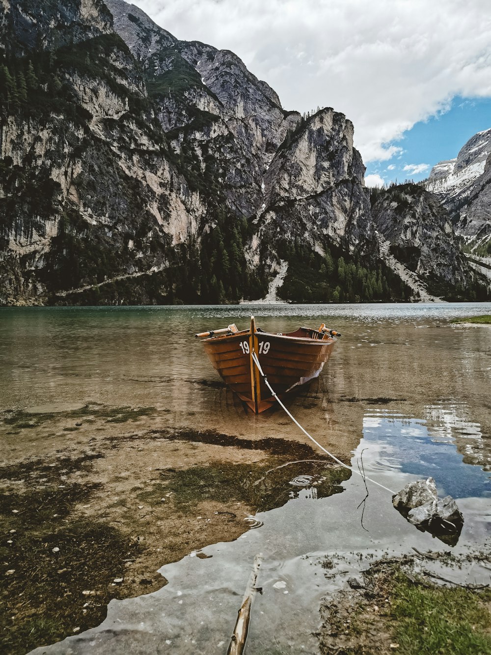 brown wooden boat on clear water shore