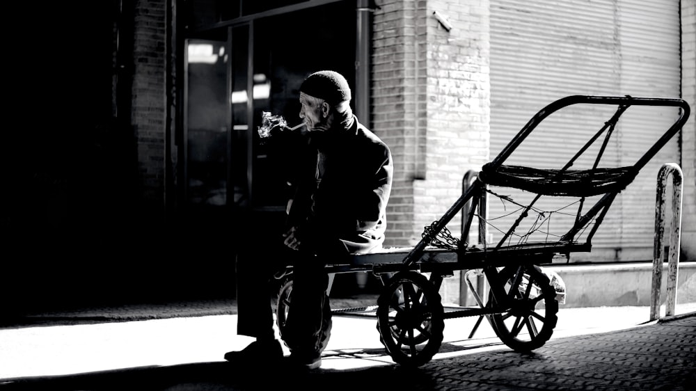 grayscale photography of person sitting on trailer