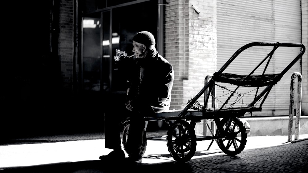 Photographie en niveaux de gris d’une personne assise sur une remorque