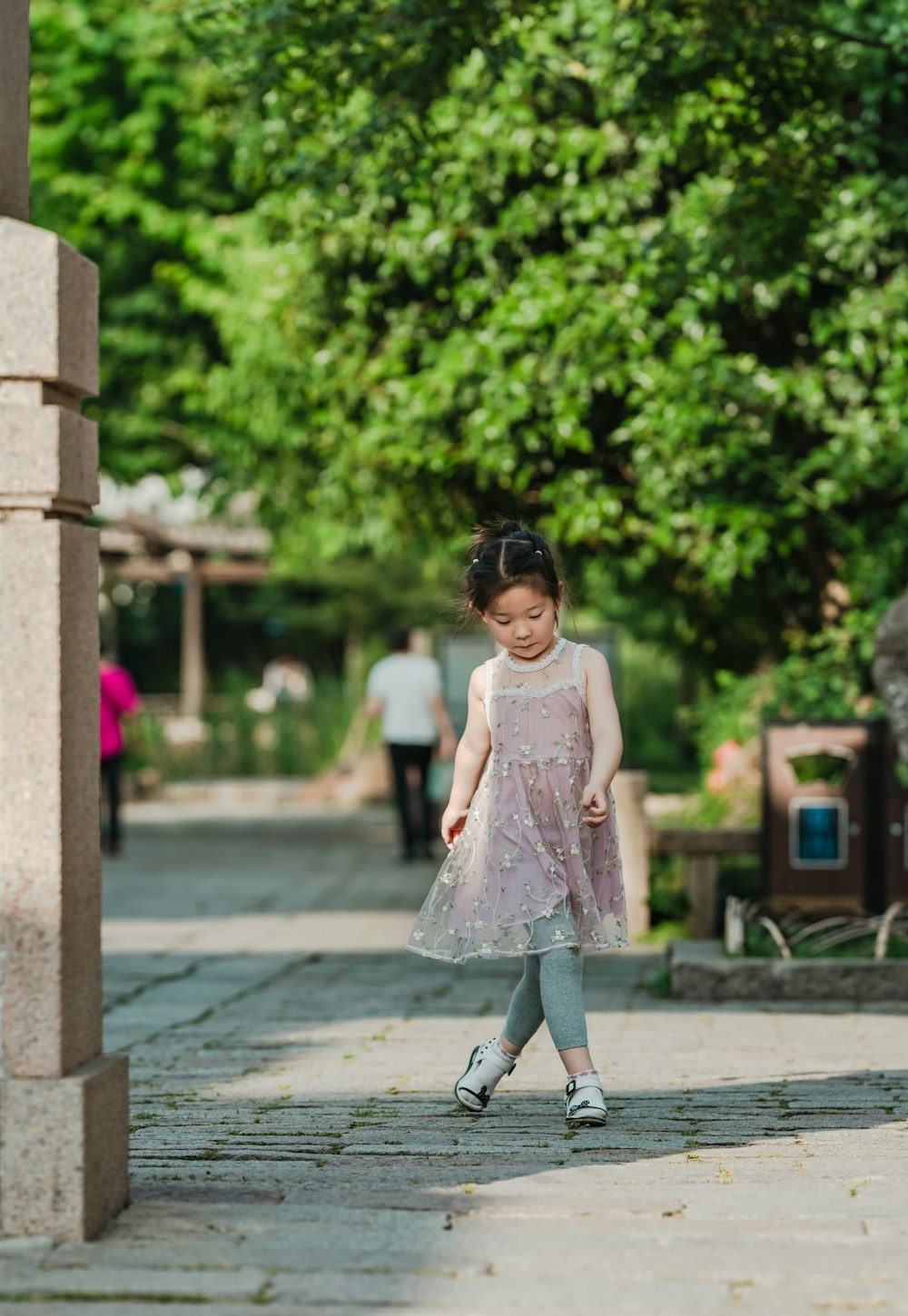 girl crossing her legs while standing under tree during daytime