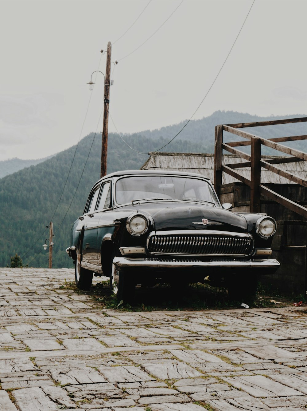 black classic car parked beside brown wooden railing