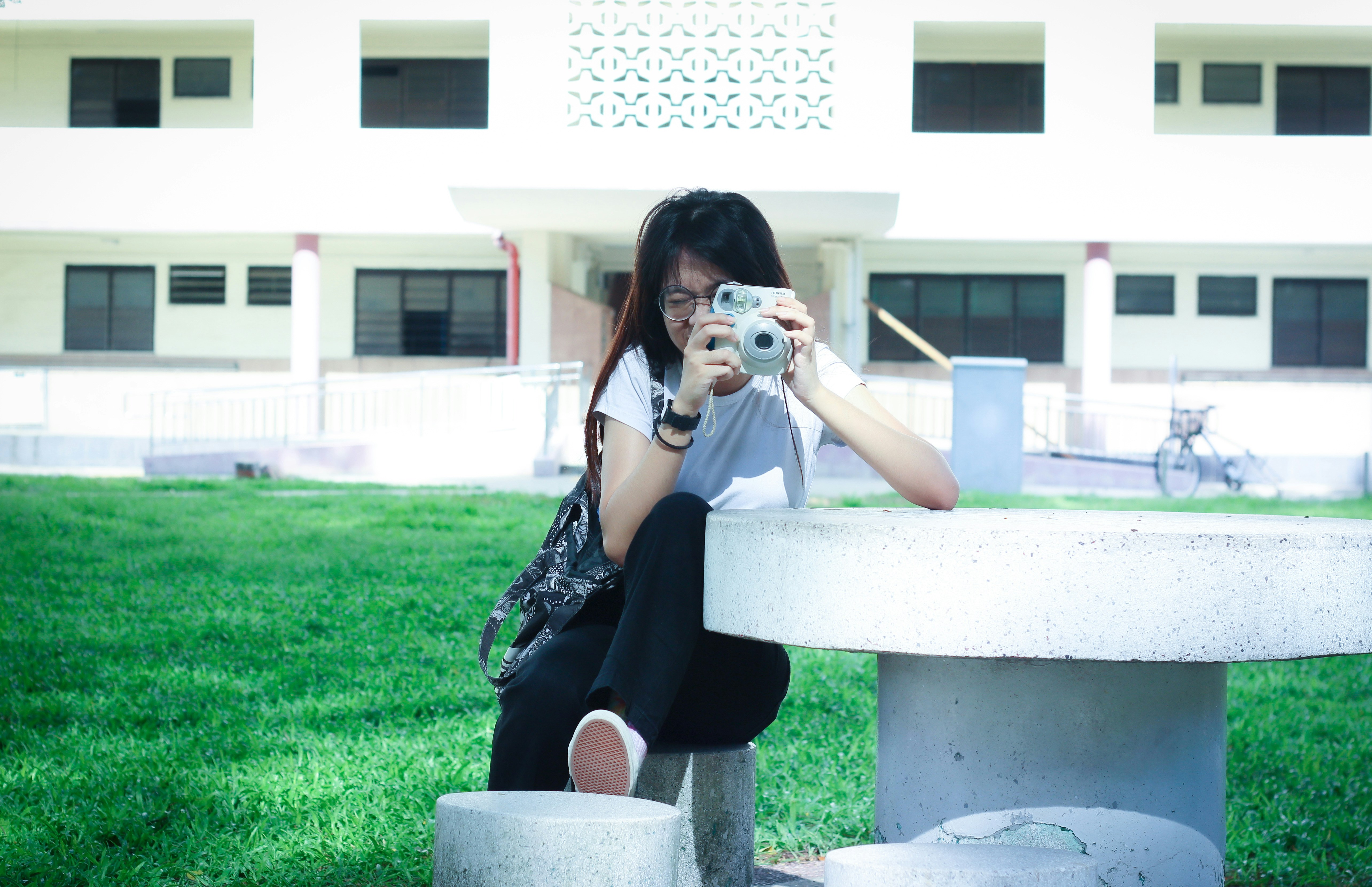 woman sitting on white concrete chair while taking photo
