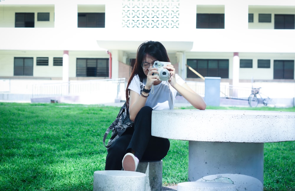 woman sitting on white concrete chair while taking photo