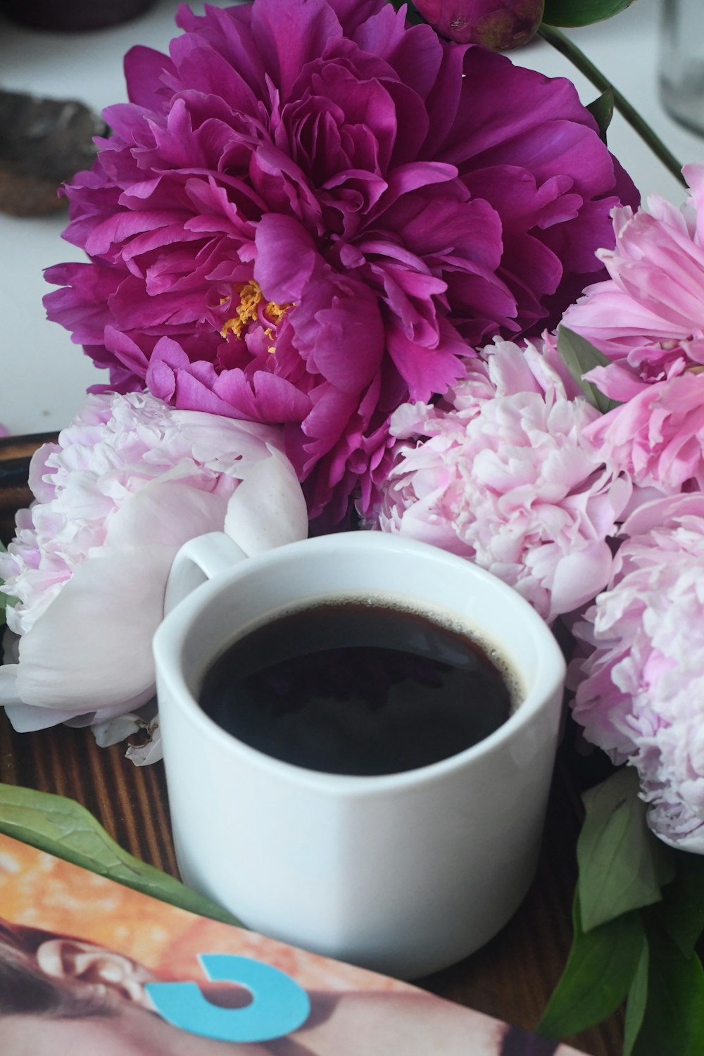 cup of coffee on table with pink flowers on side