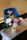 A close-up of a colorful flower arrangement with roses and lilies on a wooden table by a sunny window.