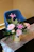 A close-up of a colorful flower arrangement with roses and lilies on a wooden table by a sunny window.