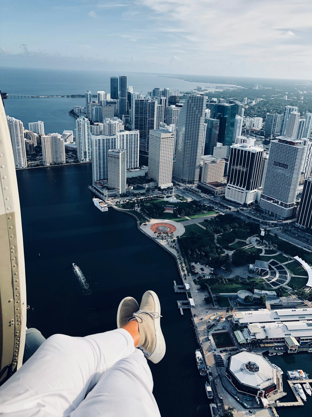 person in white pants sitting on ledge overlooking city