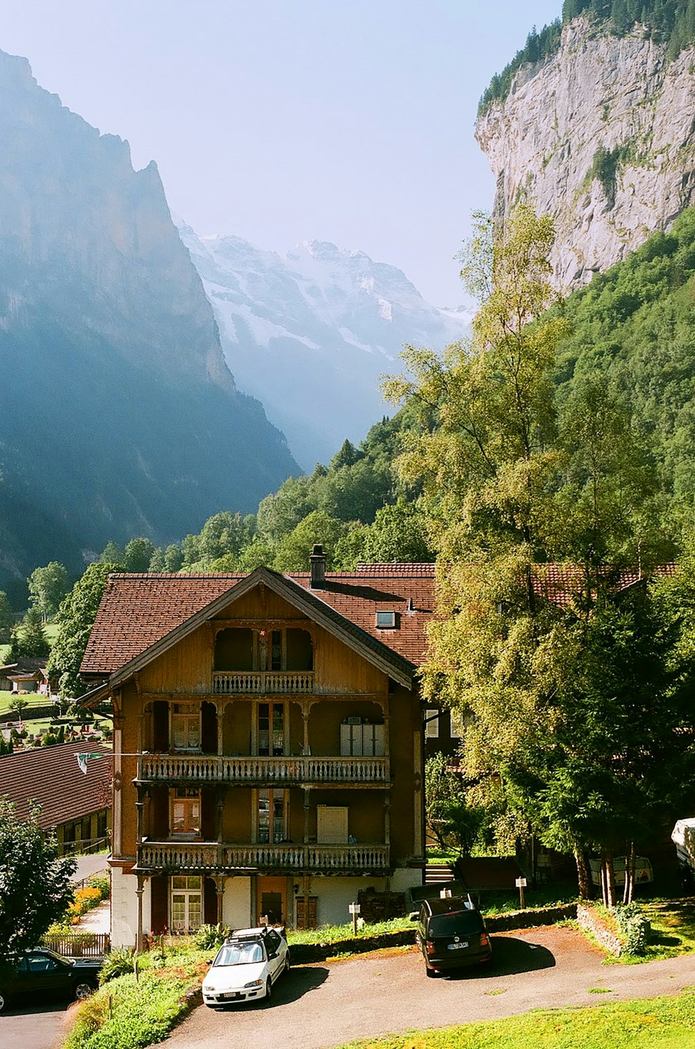 cars parked in front of house near trees during day