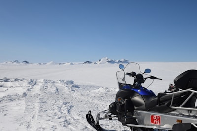 A snowmobile gliding swiftly over fresh snow under a clear blue sky.