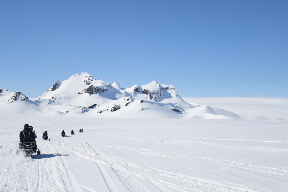 people riding snowmobiles at the field during day