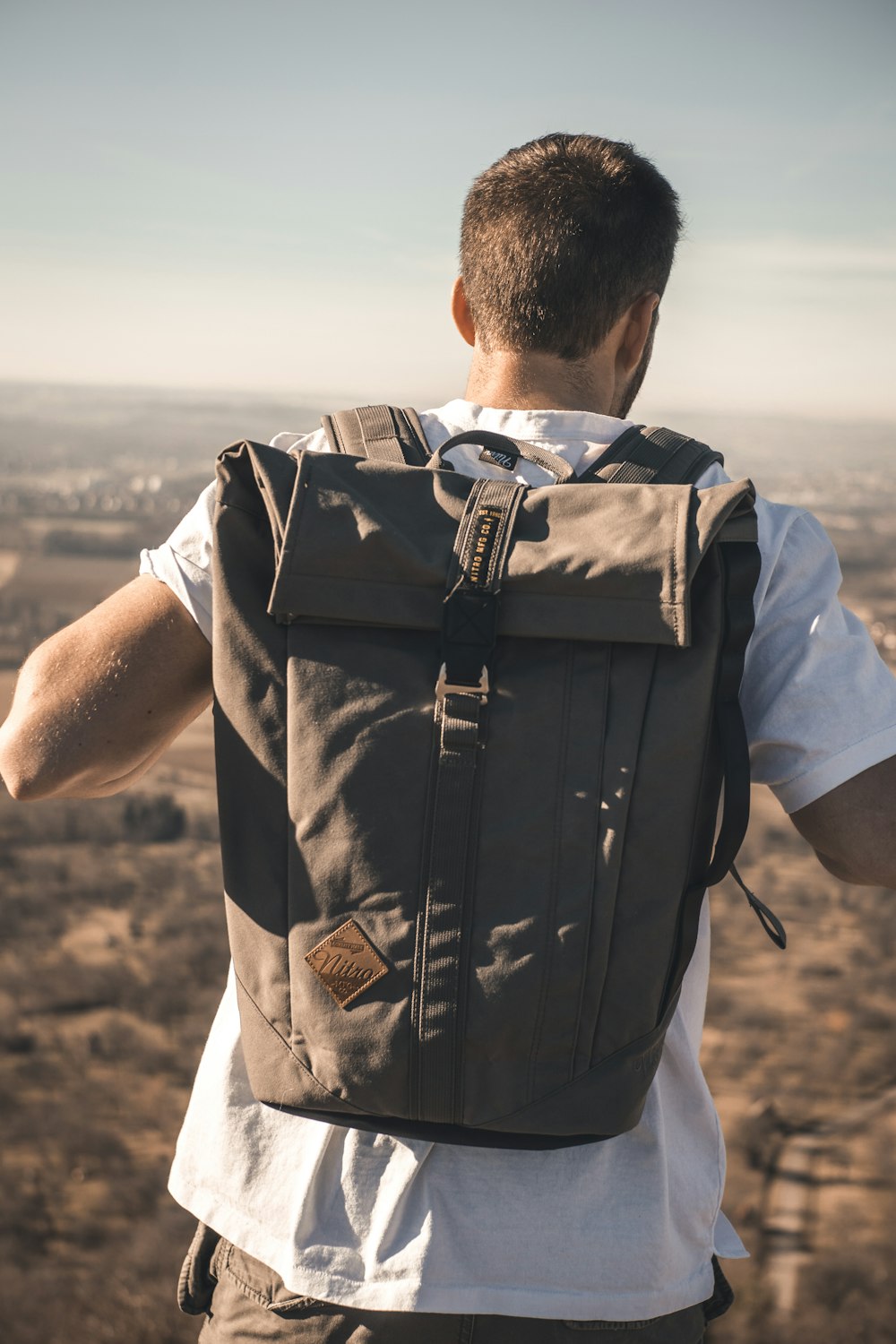 man wearing white t-shirt carrying backpack