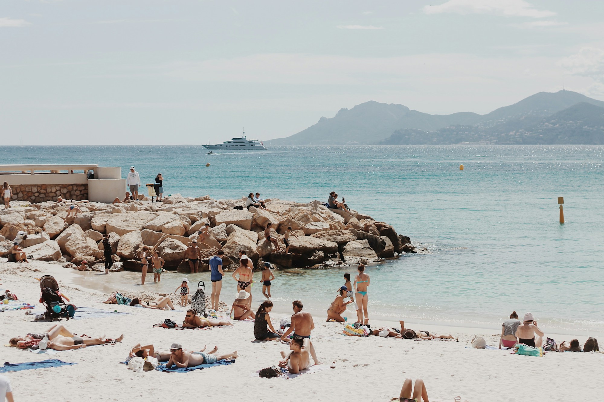 A rocky Mediterranean shore with hills across the bay
