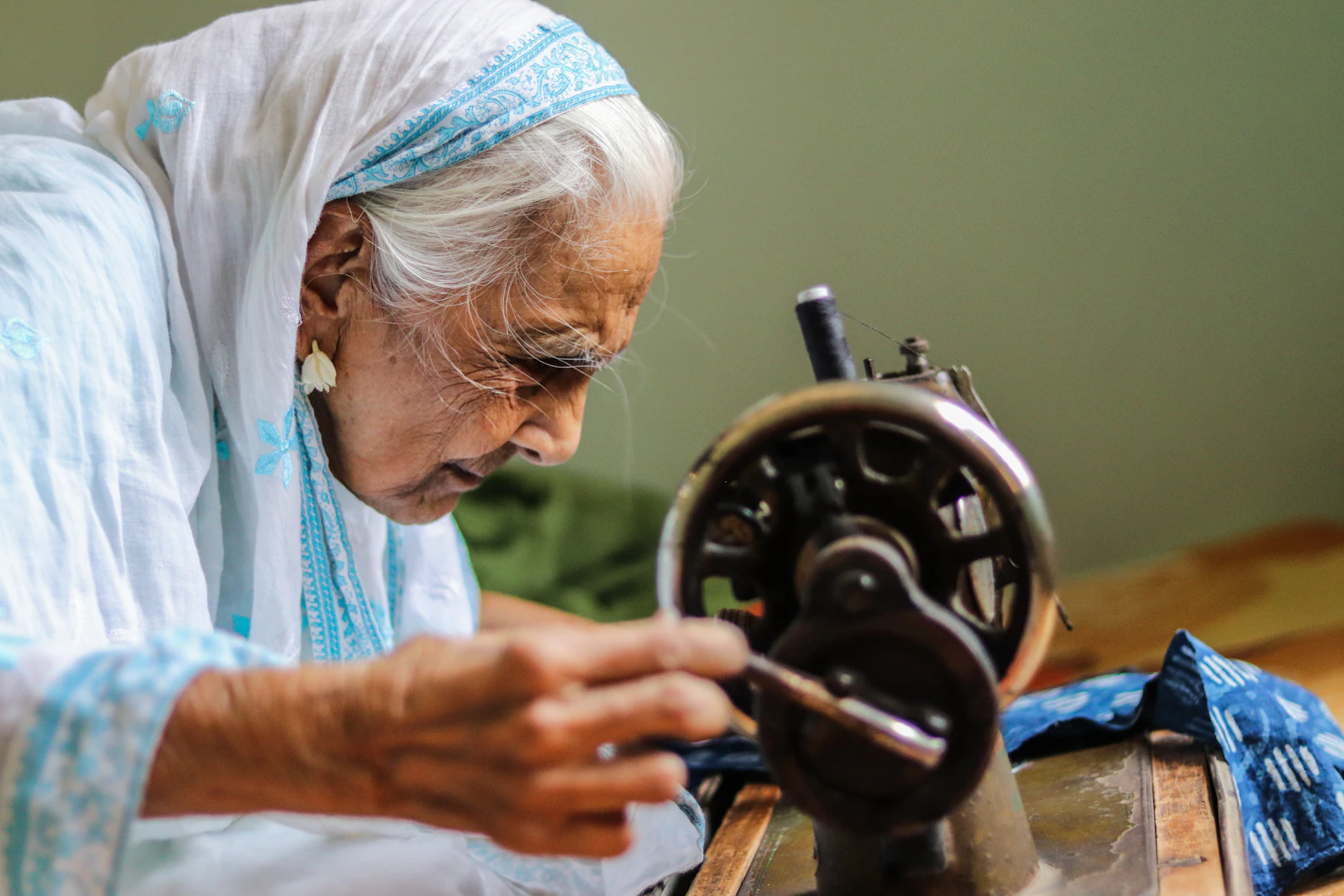 A person sewing at a machine indoors, hands guiding fabric