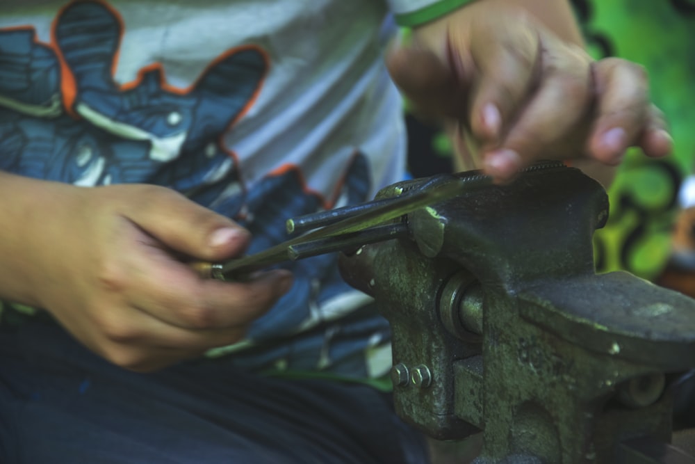 person holding gray bench vise