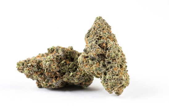 Two dense clusters of cannabis buds with visible trichomes and orange pistils. The texture appears rough and crystalline.