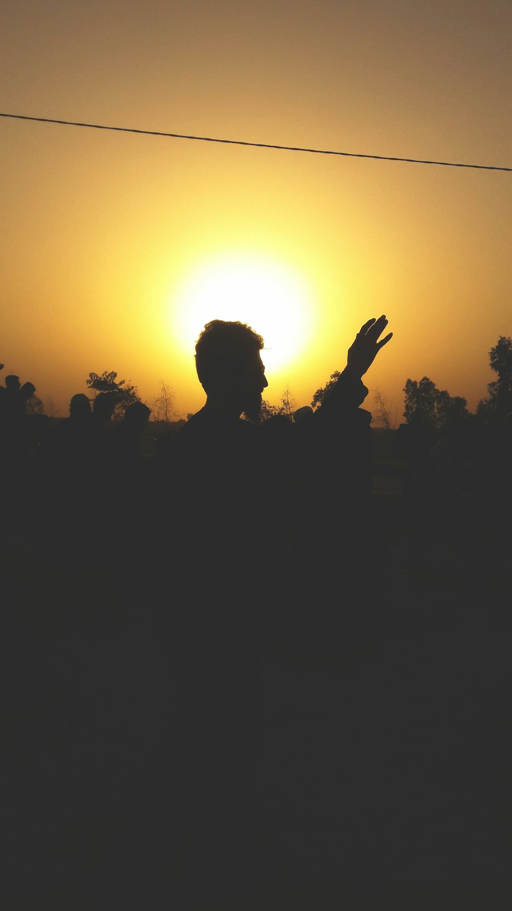 a silhouette of a man with his hand up in the air