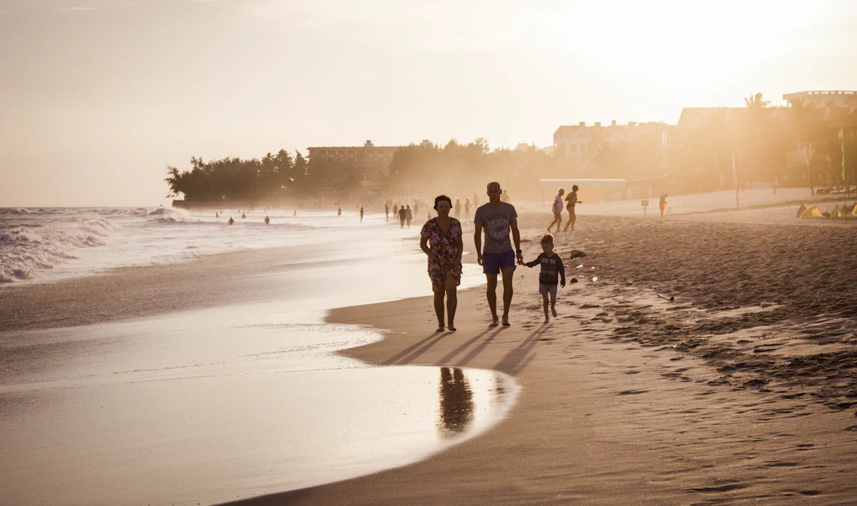 Pessoas caminhando na beira do mar ao fim de tarde