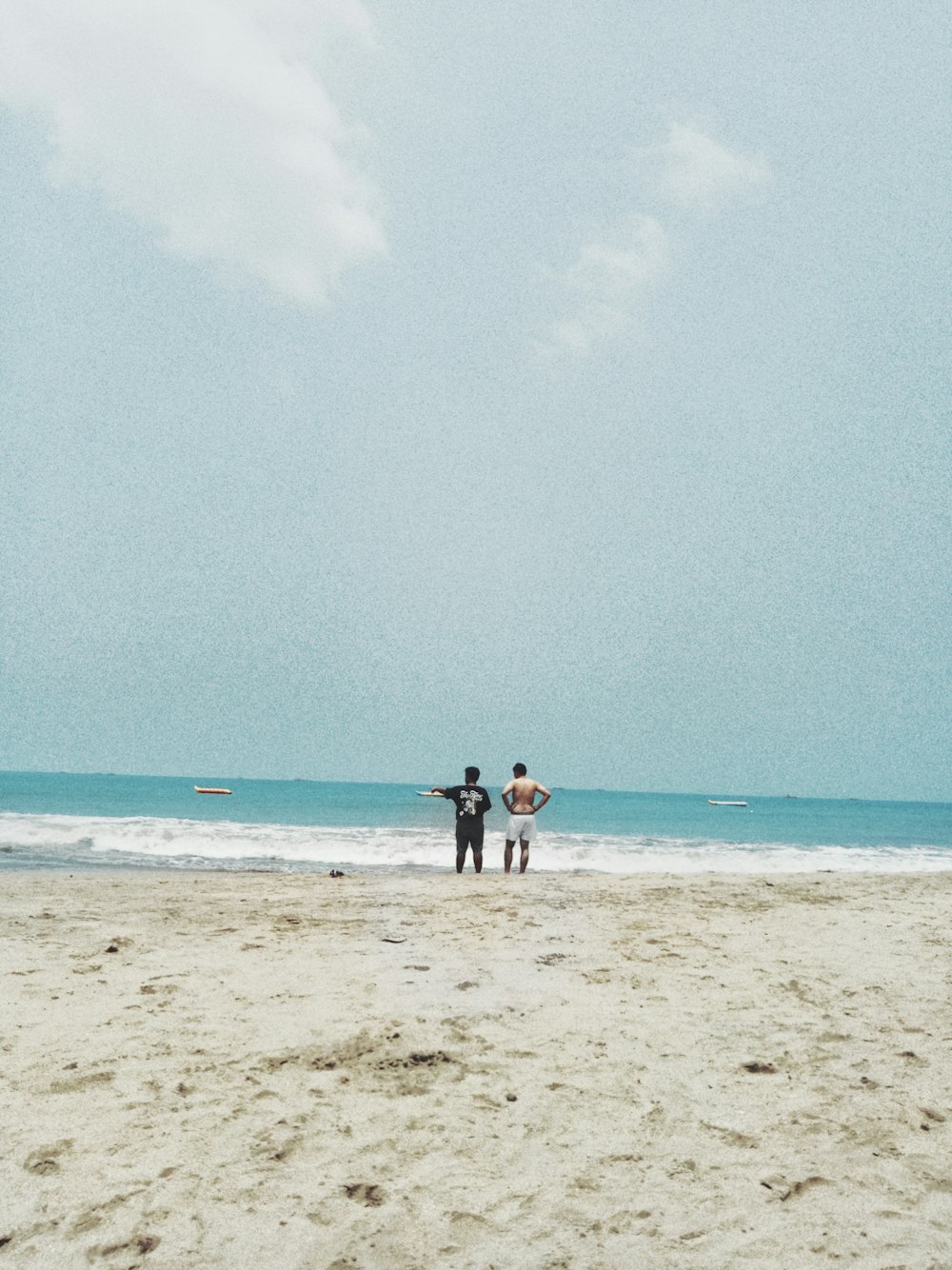 two men standing next to each other on shore