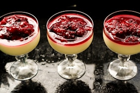 three clear short-stem wine glasses on black surface