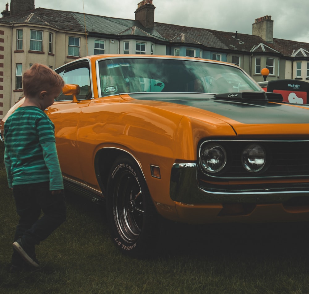 boy beside orange car