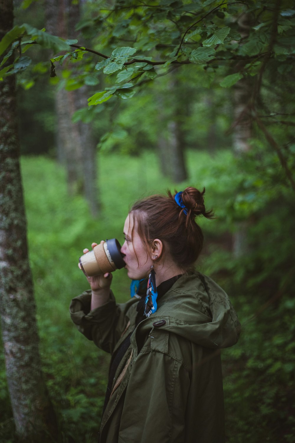 woman drinking coffee near trees