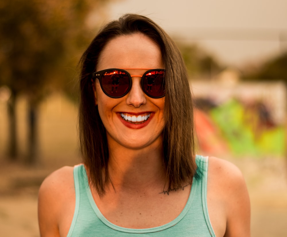 woman in green tank top wearing sunglasses and smiling