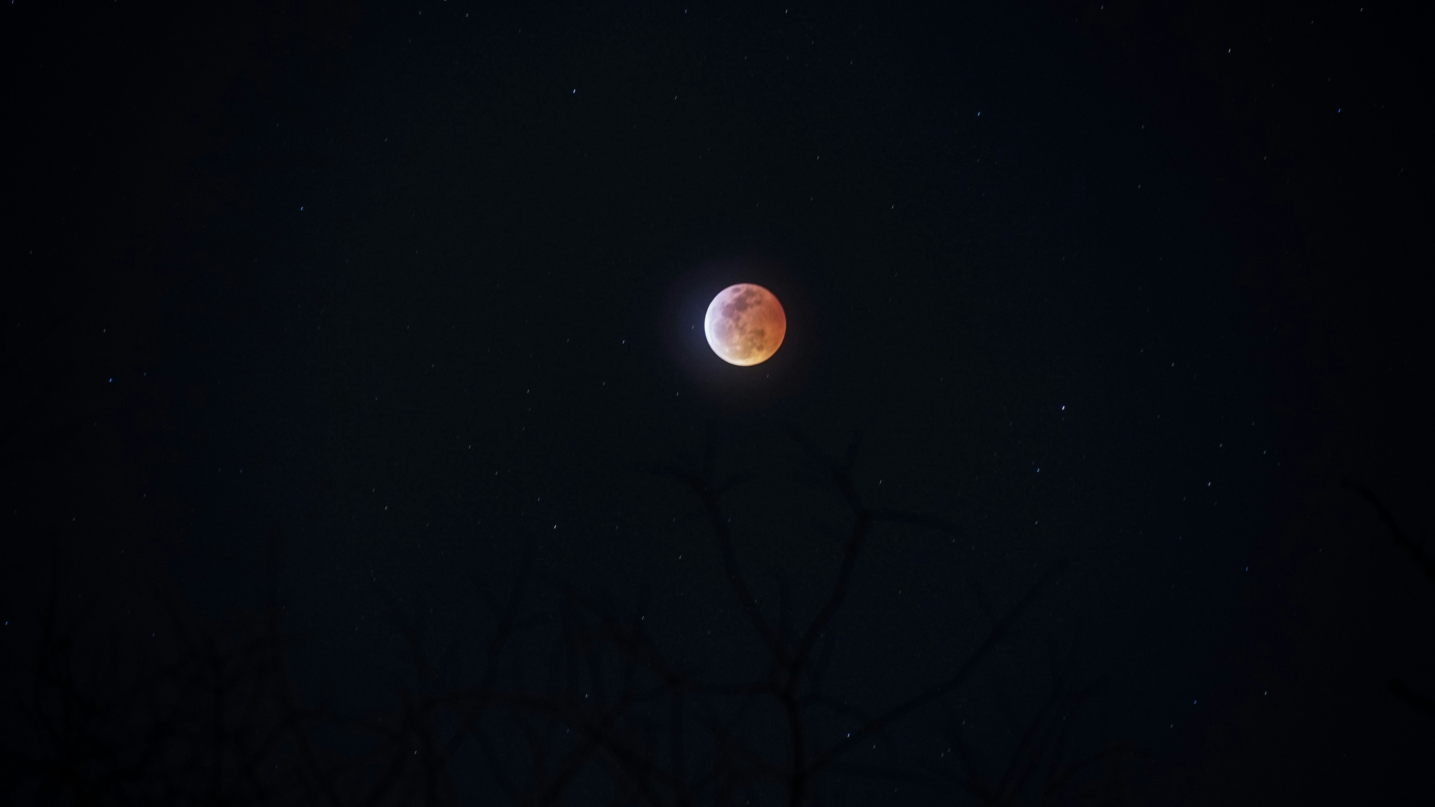 Total lunar eclipse blood moon in dark night sky, dramatic red orange color, deep space atmosphere