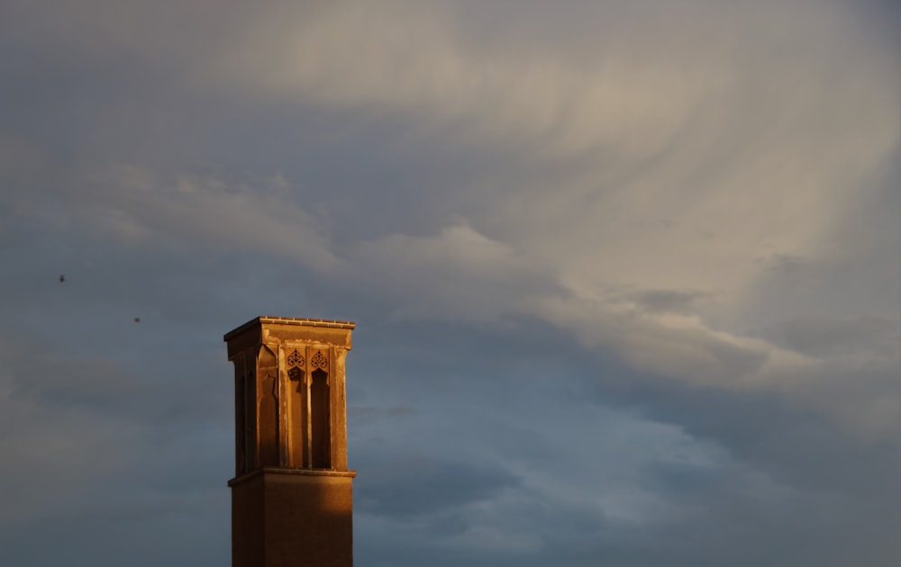 un'alta torre con un orologio su di esso sotto un cielo nuvoloso