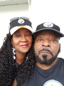 Smiling fans wearing matching printed hoodies at a sports event.