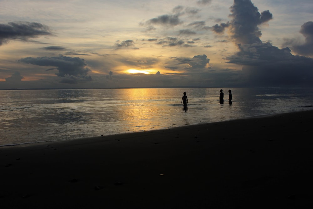 silhouette di tre persone vicino alla riva