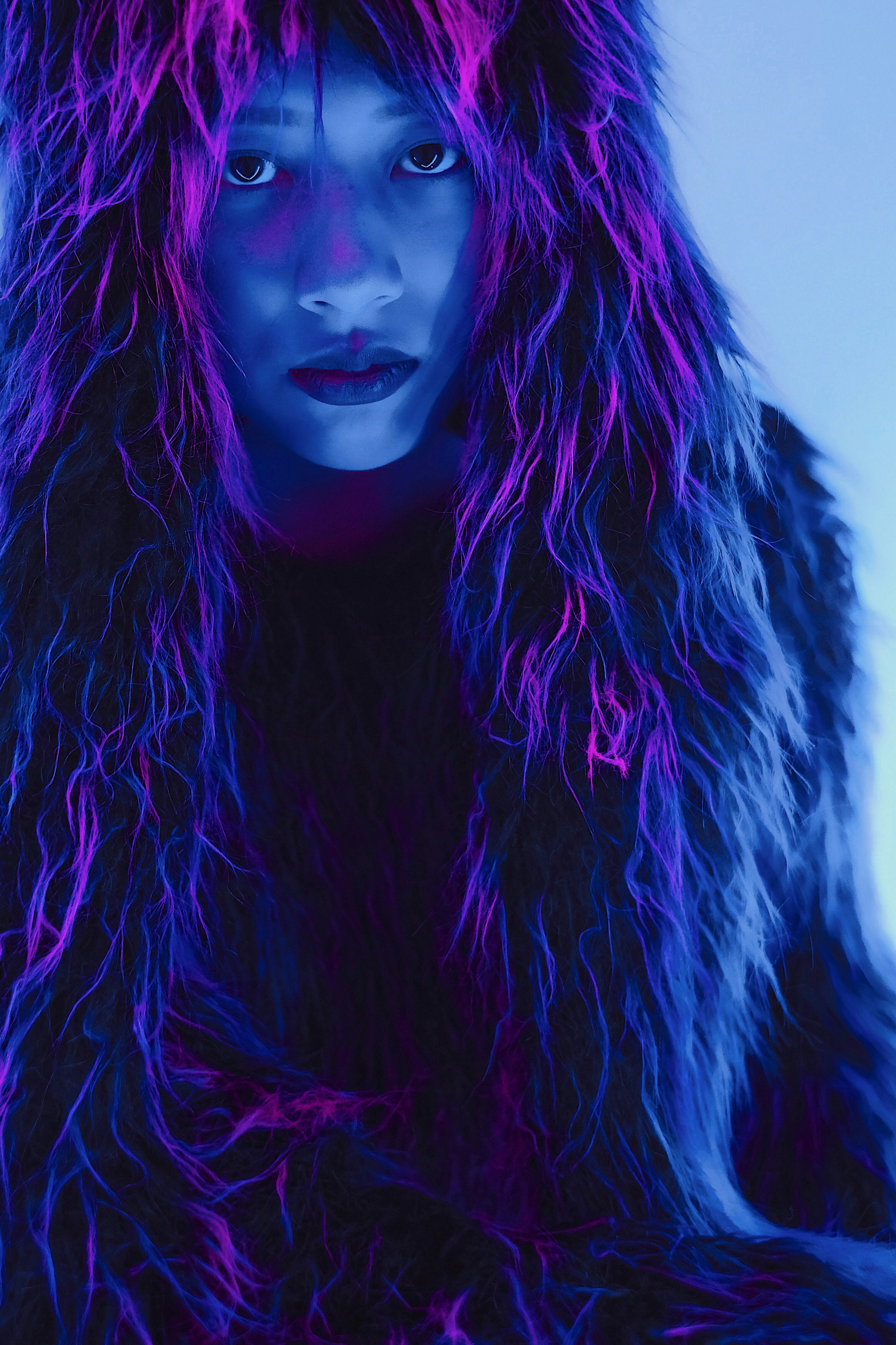 An image of a serious-faced woman draped in furs, lit in futuristic purples and blues.