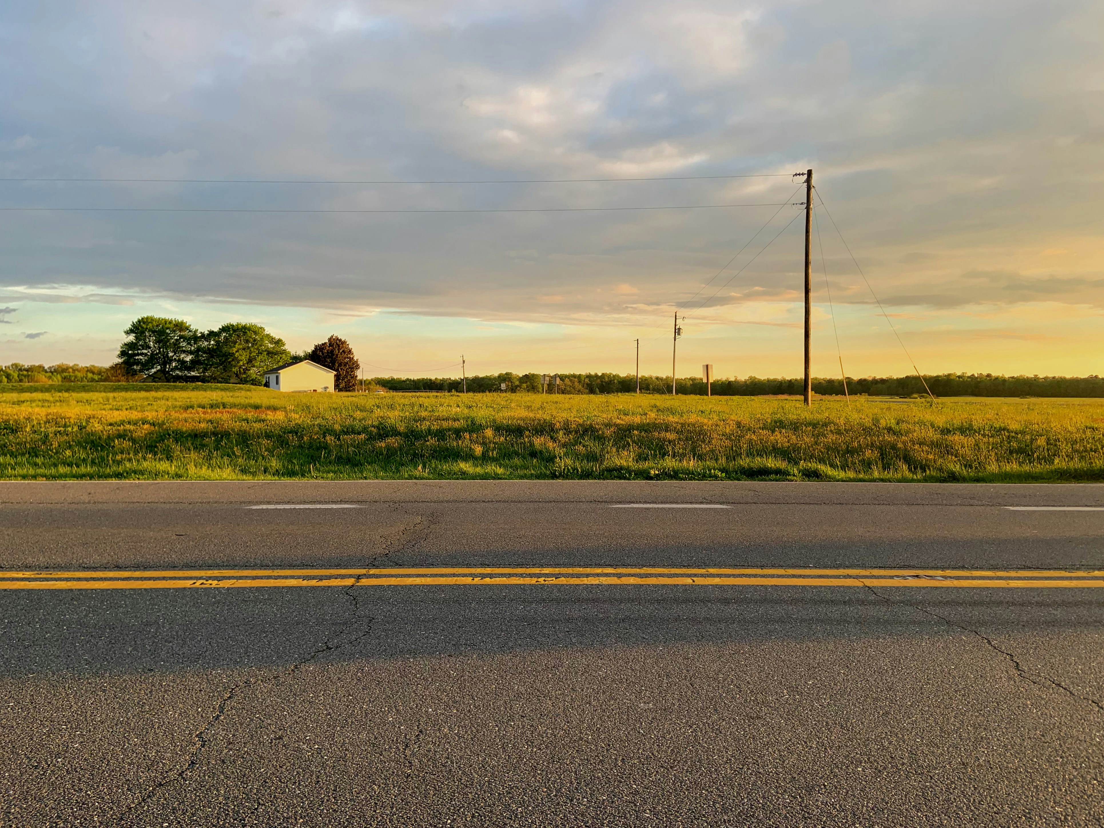 gray paved road beside green grass field