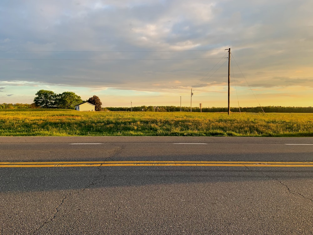 estrada pavimentada cinza ao lado do campo de grama verde