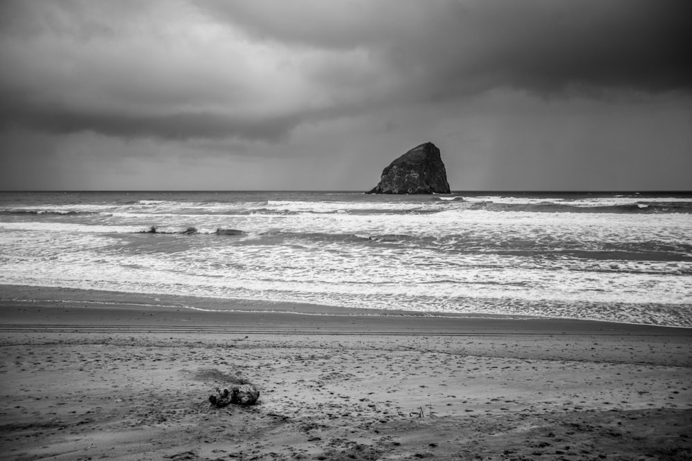grayscale photo of rock formation near shore