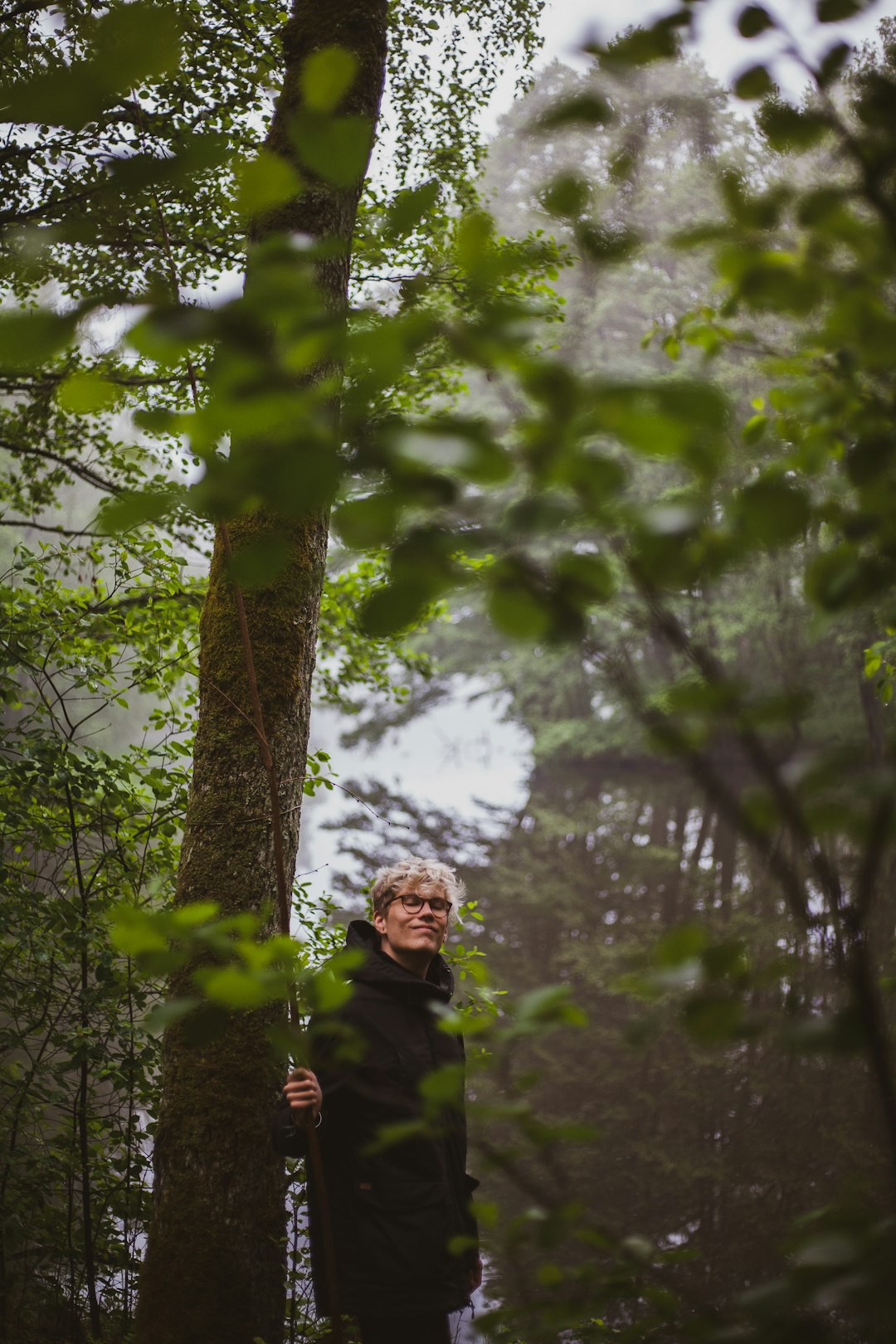 man standing beside green-leafed tree during daytime