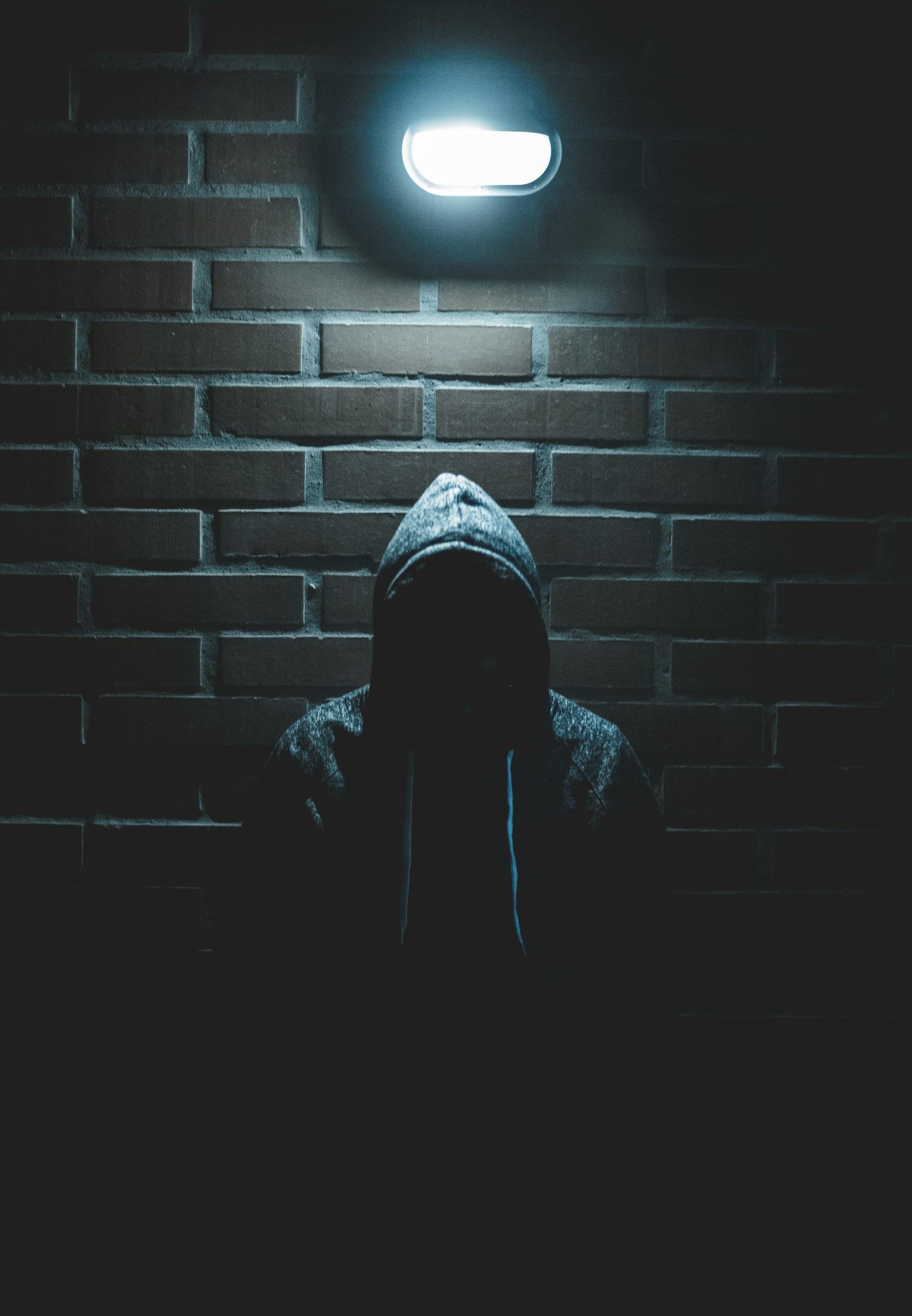 Man standing in a dark hallway wearing a hoodie - wornbee.com