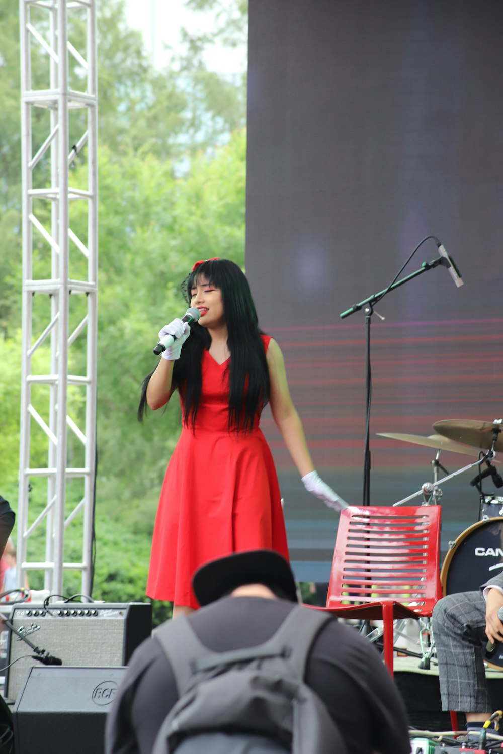 photography of woman singing near stage during daytime