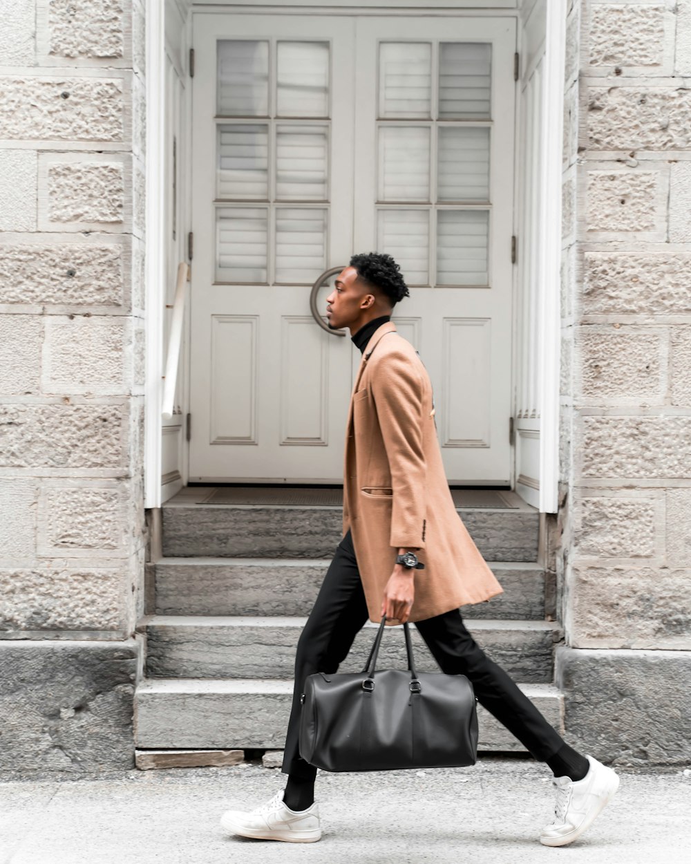 uomo che cammina sulla strada mentre tiene la borsa durante il giorno