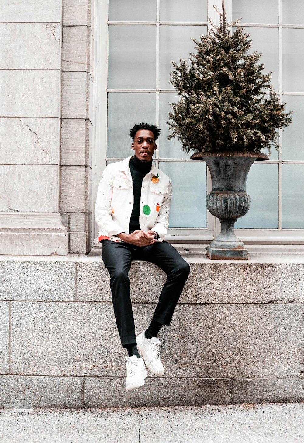 man sitting on concrete ground beside potted plant