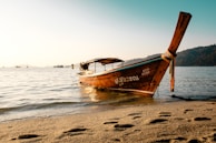 A serene beach at sunset with traditional long-tail boats resting on the shore.